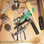 A cluttered kitchen drawer before organization